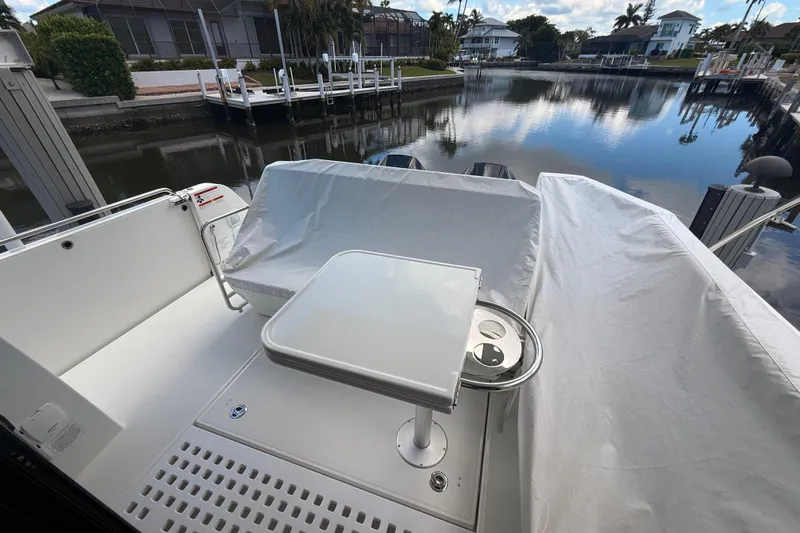  Yacht Photos Pics 2024 Beneteau Antares 11 boat deck with table, covered seating, and waterfront view.