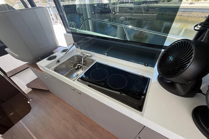  Yacht Photos Pics 2024 Beneteau Antares 11 kitchen area with sink, stove, and fan.