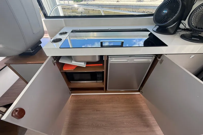  Yacht Photos Pics 2024 Beneteau Antares 11 interior kitchen with stove, sink, microwave, and refrigerator.