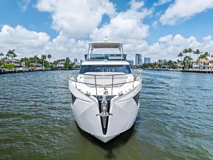 Lobster Tails Yacht Photos Pics 2023 Absolute 52 FLY yacht on water, clear sky, palm trees, and cityscape in background.