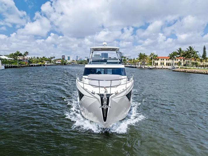 Lobster Tails Yacht Photos Pics 2023 Absolute 52 FLY yacht cruising on a scenic waterway under a partly cloudy sky.