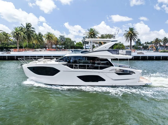 Lobster Tails Yacht Photos Pics 2023 Absolute 52 FLY yacht cruising on a sunny day, surrounded by palm trees and blue skies.