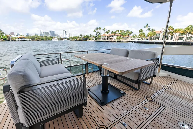 Lobster Tails Yacht Photos Pics Luxury deck of 2023 Absolute 52 FLY yacht with seating and table, overlooking waterfront.