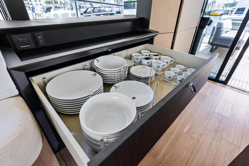 Lobster Tails Yacht Photos Pics Drawer with neatly arranged white dishes and cups on Absolute 52 FLY yacht, 2023 model.