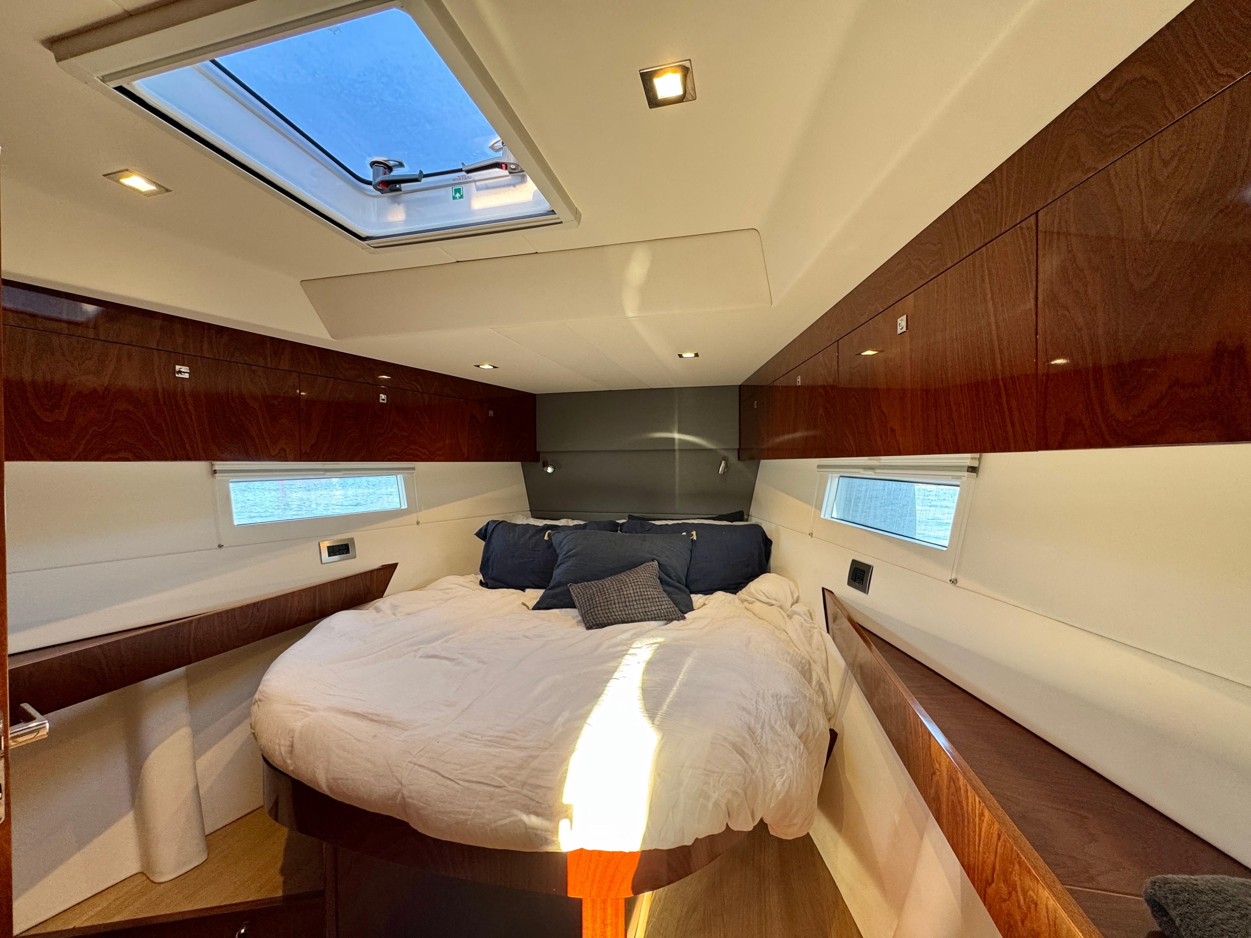 Luxurious cabin interior of 2015 Amel 55 yacht with skylight and cozy bedding.