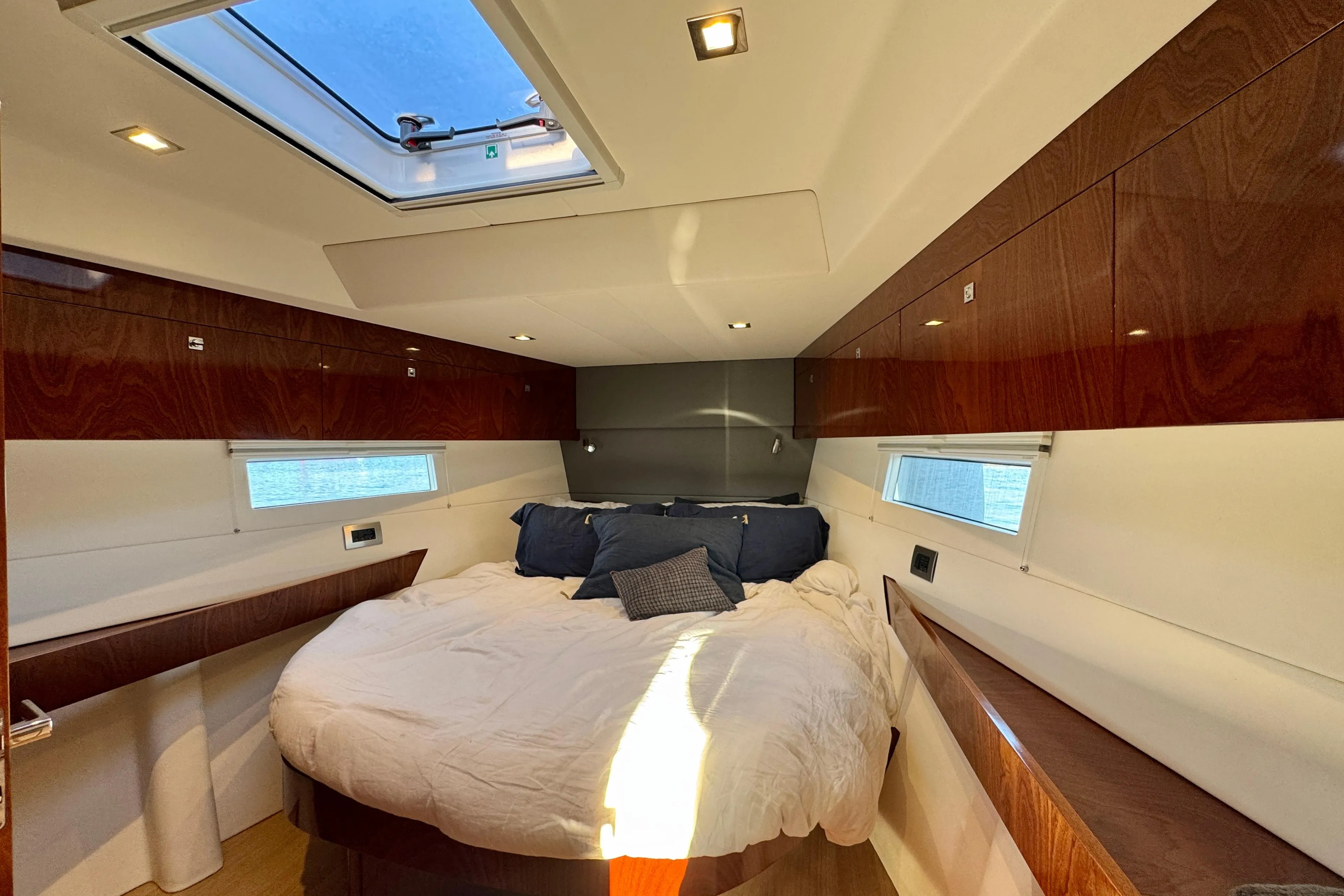 Luxurious cabin interior of 2015 Amel 55 yacht with skylight and cozy bedding.