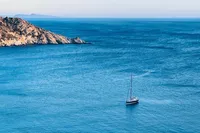 Sailboat Solaris 50 (2019) cruising near rocky coastline in clear blue sea.