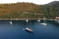 Sailboats anchored in a serene bay with lush green hills, featuring a 2019 Solaris 50.