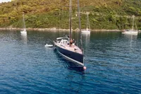 Sailing yacht Solaris 50, 2019 model, anchored in serene bay with lush green hills.