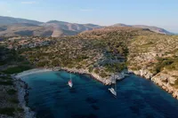 Aerial view of two sailboats in a secluded bay surrounded by rocky hills.