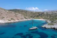 Sailing yacht Solaris 50 in a serene turquoise bay, surrounded by rocky hills.