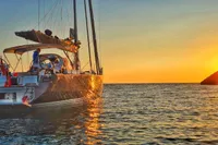 Sailing yacht Solaris 50 at sunset, 2019 model, anchored near a rocky coastline.