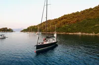 Sailing yacht Solaris 50, 2019 model, cruising in a serene bay with lush green hills.