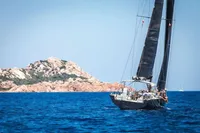 Sailing yacht Solaris 50, 2019 model, cruising near rocky coastline in clear blue waters.
