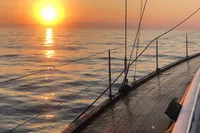 Sailing on Solaris 50 yacht at sunset, calm sea reflecting golden sunlight.