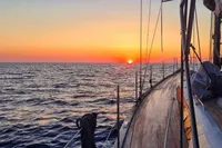 Sailing on a 2019 Solaris 50 yacht at sunset over calm ocean waters.