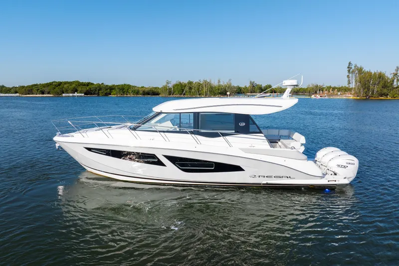 Our Trade Yacht Photos Pics 2024 Regal 42 XO luxury yacht cruising on a serene lake under clear blue skies.