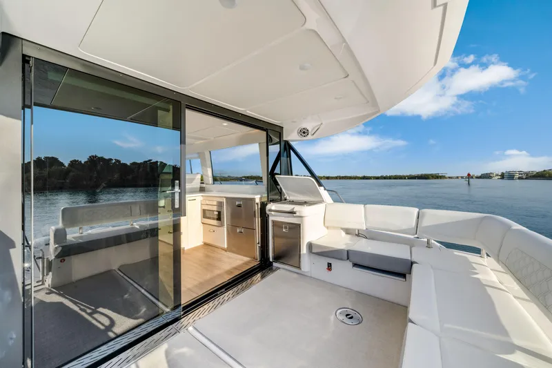 Our Trade Yacht Photos Pics 2024 Regal 42 XO yacht interior with modern kitchen and seating, overlooking serene water view.