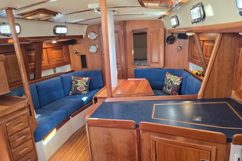 Sail Fourth Yacht Photos Pics Interior of a 2001 Tartan 3700 sailboat with blue seating and wooden cabinetry.