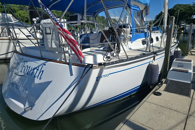 Sail Fourth Yacht Photos Pics Tartan 3700 sailboat from 2001 docked, featuring American flag and blue canopy.