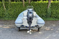 2022 AB Inflatables 11 ALX boat with outboard motor on trailer, parked on gravel.
