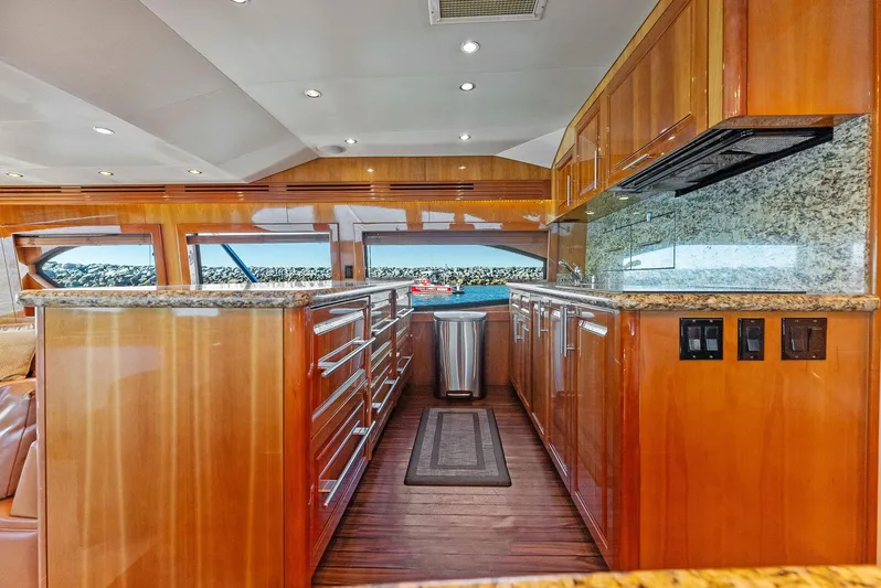 Chupacabra Yacht Photos Pics Luxurious kitchen interior of 2007 Hatteras 64 Convertible yacht with wooden cabinetry and granite countertops.