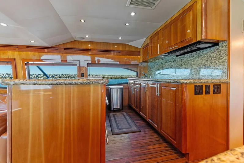 Chupacabra Yacht Photos Pics Luxurious kitchen interior of a 2007 Hatteras 64 Convertible yacht with wooden cabinetry and granite countertops.