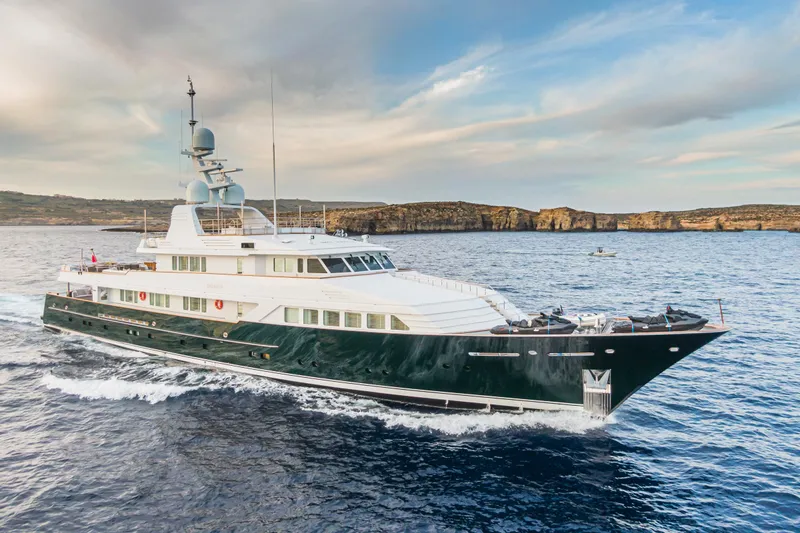 Emerald Yacht Photos Pics Luxurious 1990 Feadship yacht cruising on open water under a partly cloudy sky.