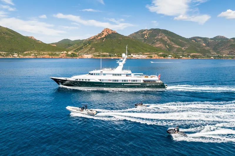 Emerald Yacht Photos Pics Luxurious 1990 Feadship yacht cruising with speedboats in scenic coastal waters.