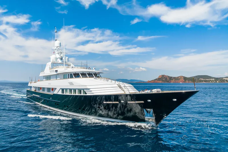 Emerald Yacht Photos Pics Luxurious 1990 Feadship yacht cruising on open sea under clear blue sky.