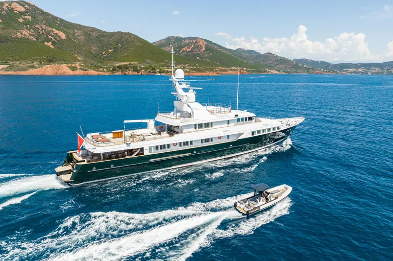 Emerald Yacht Photos Pics Luxury 1990 Feadship yacht cruising with tender in scenic coastal waters.