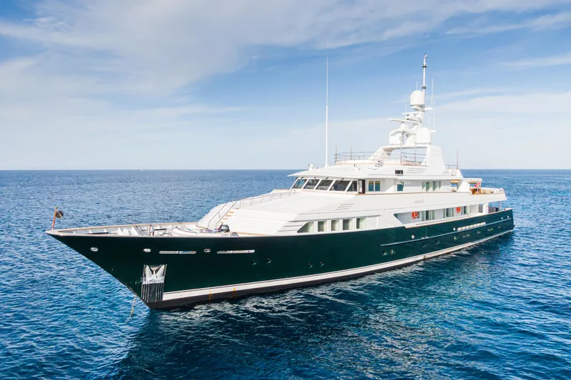 Emerald Yacht Photos Pics Luxurious 1990 Feadship yacht cruising on open sea under clear blue sky.