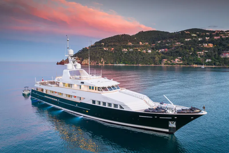 Emerald Yacht Photos Pics Luxurious 1990 Feadship yacht cruising near scenic coastline at sunset.