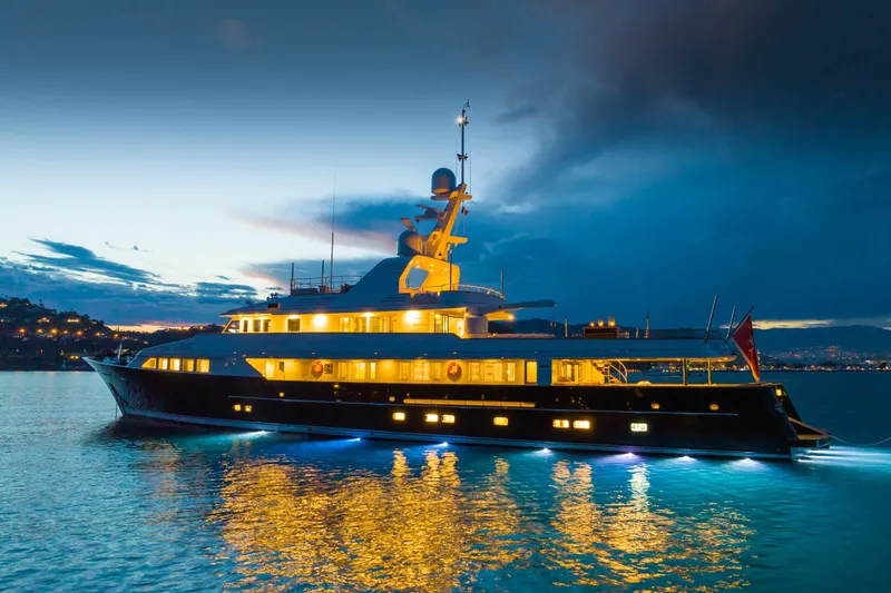 Emerald Yacht Photos Pics Luxurious 1990 Feadship yacht illuminated at dusk on calm waters.