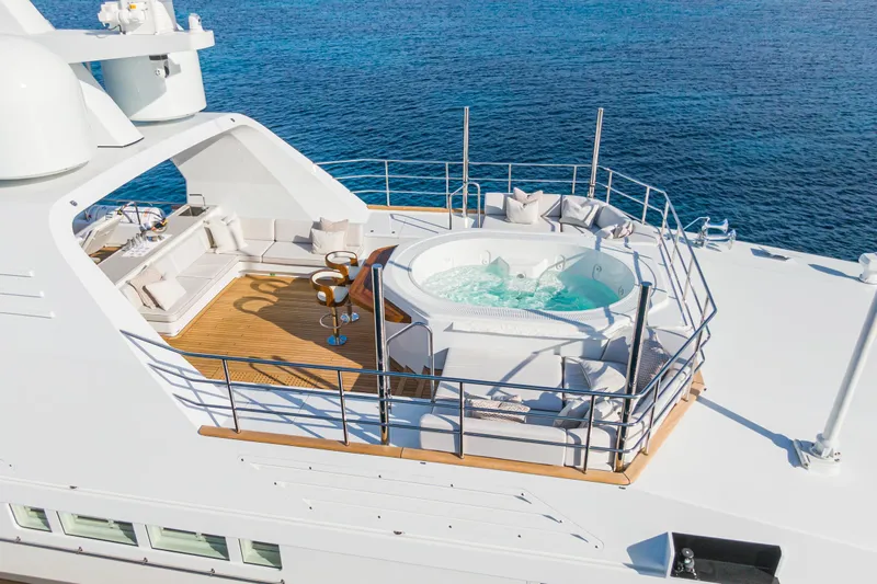 Emerald Yacht Photos Pics Luxurious 1990 Feadship yacht deck with jacuzzi and seating area, overlooking the ocean.