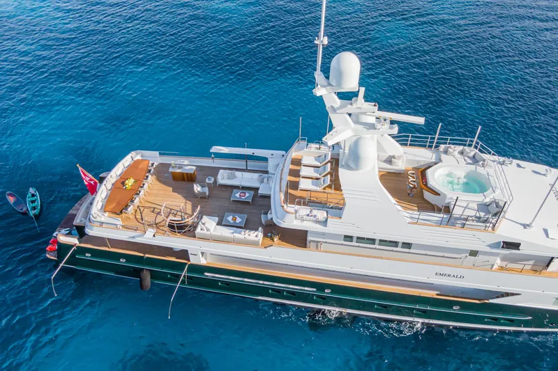 Emerald Yacht Photos Pics Luxurious 1990 Feadship yacht with deck jacuzzi, anchored in clear blue waters.