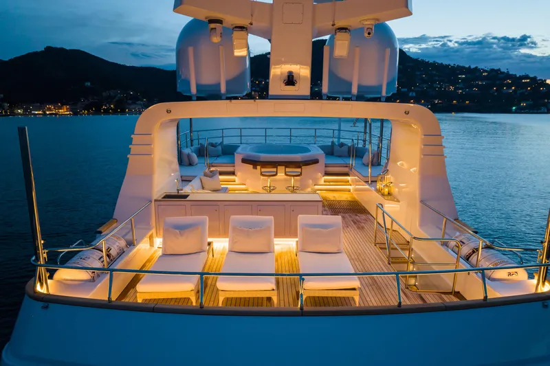Emerald Yacht Photos Pics Luxurious 1990 Feadship yacht deck at sunset, featuring elegant seating and ambient lighting.