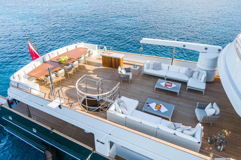 Emerald Yacht Photos Pics Luxurious 1990 Feadship yacht deck with elegant seating and dining area, overlooking serene ocean waters.
