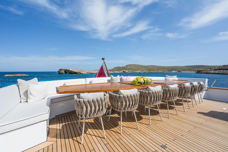 Emerald Yacht Photos Pics Luxurious Feadship yacht deck with elegant dining setup, ocean view, and clear blue sky.