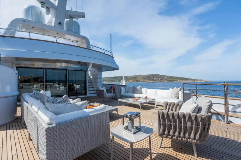 Emerald Yacht Photos Pics Luxurious 1990 Feadship yacht deck with elegant seating and ocean view.