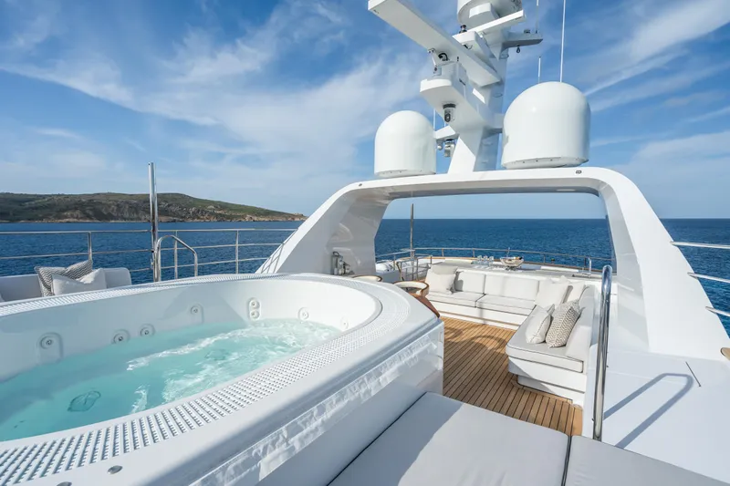 Emerald Yacht Photos Pics Luxurious 1990 Feadship yacht deck with jacuzzi and seating, overlooking serene ocean views.
