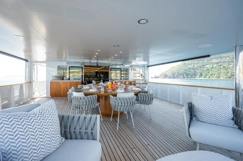 Emerald Yacht Photos Pics Luxurious 1990 Feadship yacht deck with elegant dining setup and scenic ocean view.