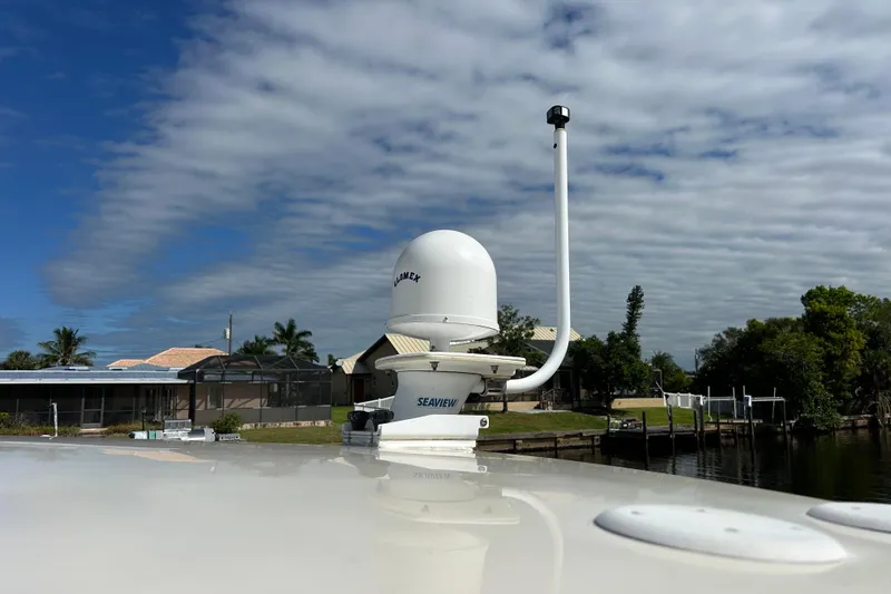 Eagle Yacht Photos Pics 2008 Mainship Pilot 34 boat with radar equipment, docked near waterfront homes under a cloudy sky.