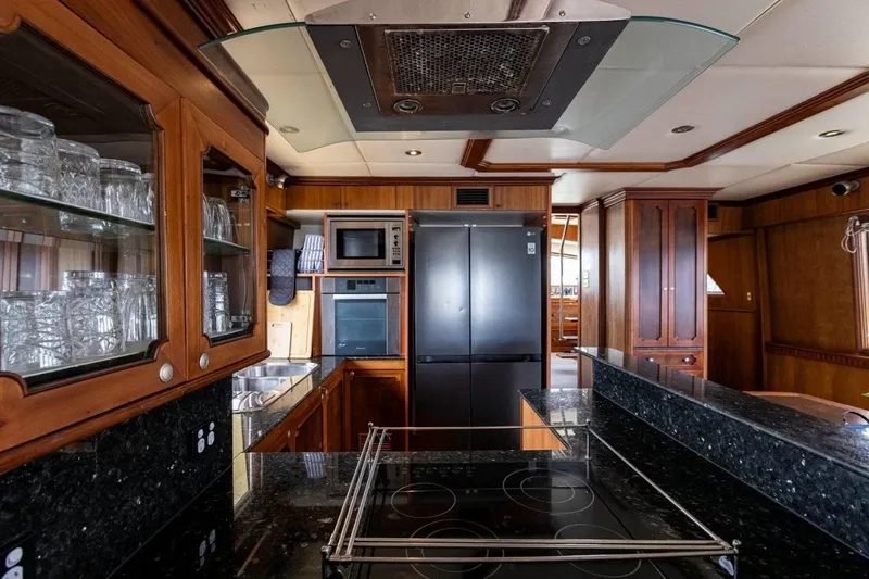Seabear Yacht Photos Pics Luxurious kitchen interior on 2006 Amanda 72 Explorer yacht with modern appliances and wooden cabinetry.
