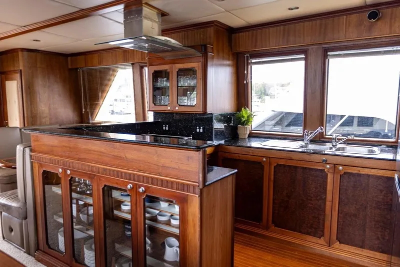 Seabear Yacht Photos Pics Luxurious wooden yacht kitchen interior with modern amenities, featuring glass cabinets and large windows.