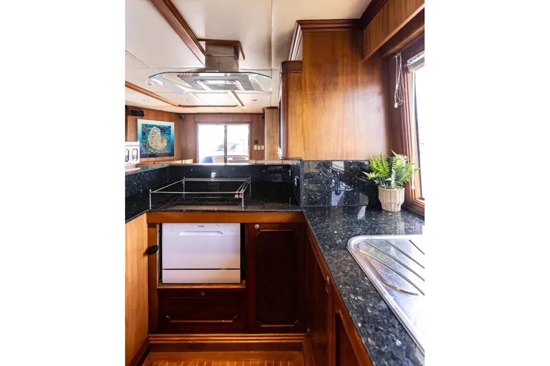 Seabear Yacht Photos Pics Luxurious yacht kitchen with wood cabinetry, black granite countertops, and a potted plant. Amanda 72 Explorer.