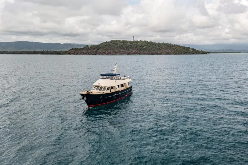 Seabear Yacht Photos Pics Luxury yacht Amanda 72 Explorer (2006) cruising near a scenic island under cloudy skies.