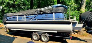 2017 Regency 220 DL3 pontoon boat on trailer, covered, parked in wooded area.