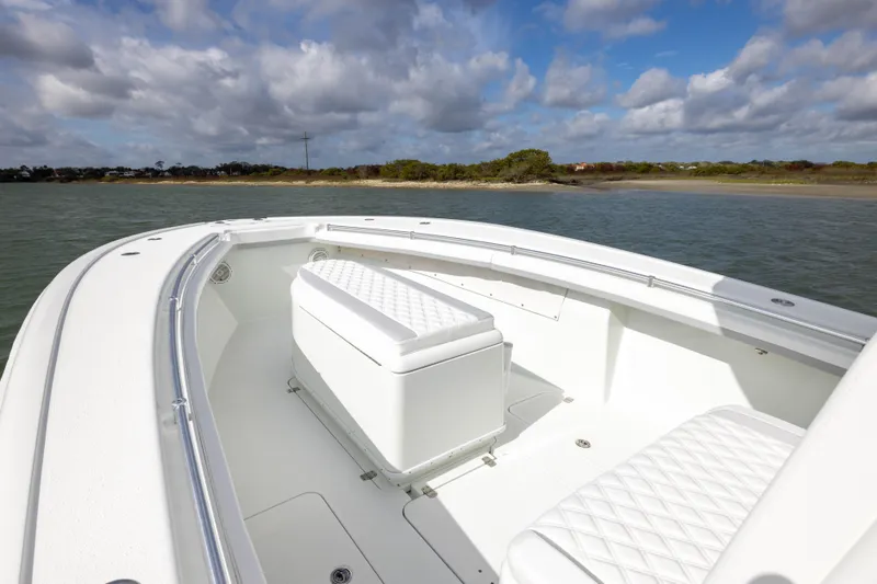 Done Deal Yacht Photos Pics 2014 Yellowfin 32 Offshore boat with white seating, cruising near a scenic shoreline.