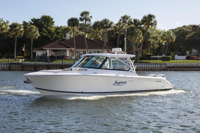 Joysea Yacht Photos Pics 2019 Pursuit DC 325 Dual Console boat cruising on a sunny day near waterfront homes.